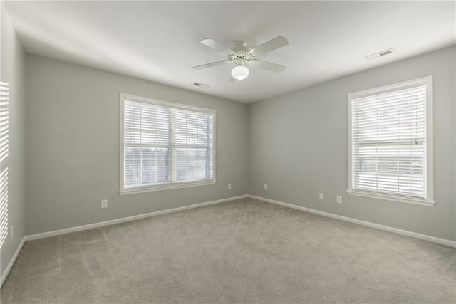 carpeted spare room with ceiling fan and plenty of natural light