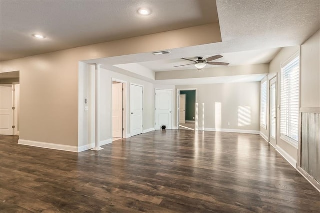 unfurnished room with ceiling fan, a tray ceiling, and dark hardwood / wood-style flooring