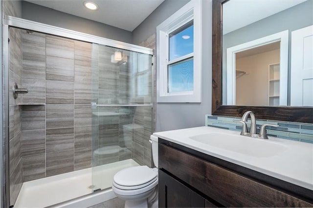 bathroom featuring toilet, vanity, and a shower with shower door