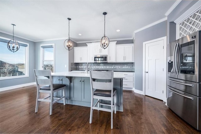 kitchen with white cabinetry, stainless steel appliances, decorative backsplash, hanging light fixtures, and a center island with sink