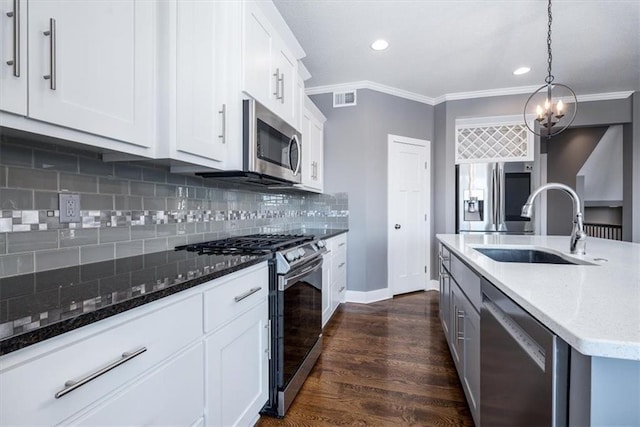 kitchen featuring white cabinets, stainless steel appliances, dark stone countertops, sink, and hanging light fixtures