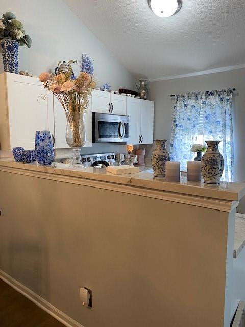 kitchen with white cabinets, stove, kitchen peninsula, and a textured ceiling