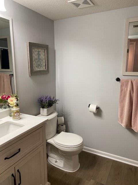 bathroom with vanity, wood-type flooring, a textured ceiling, and toilet