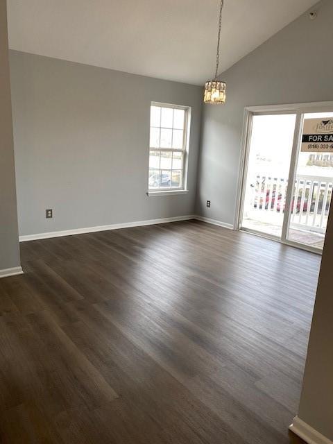 unfurnished room featuring vaulted ceiling, dark hardwood / wood-style floors, and a chandelier