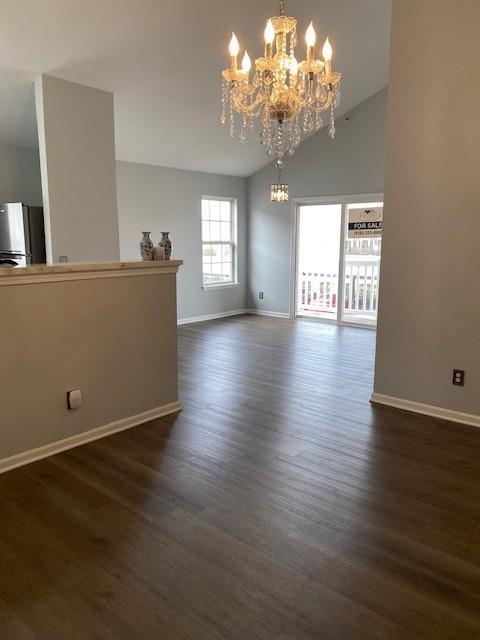 spare room with lofted ceiling, dark hardwood / wood-style floors, and a chandelier