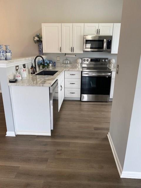 kitchen with light stone counters, sink, stainless steel appliances, and white cabinets