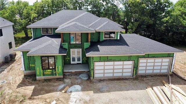 16900 Parkhill St, Overland Park, KS 66221 - property in mid-construction featuring roof with shingles, french doors, a garage, driveway, and view of scattered trees
