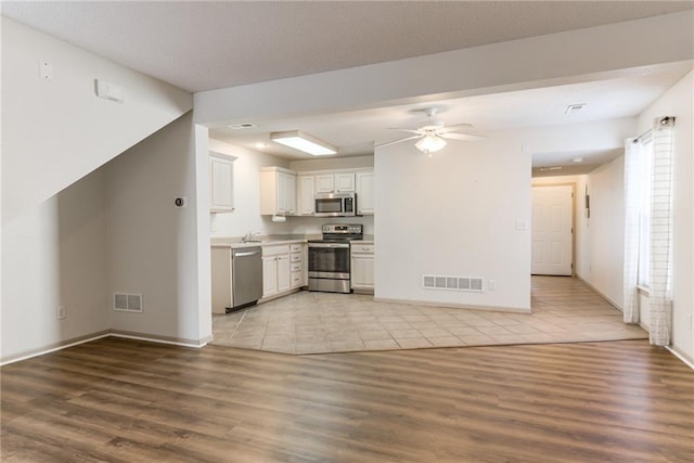 kitchen with ceiling fan, light hardwood / wood-style floors, white cabinets, and appliances with stainless steel finishes