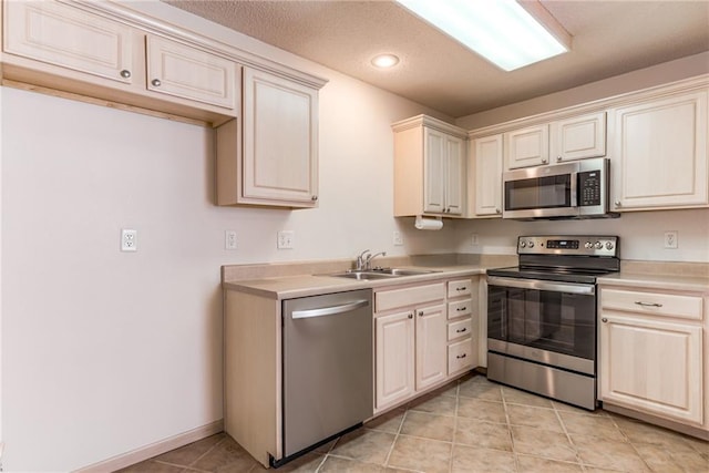 kitchen with appliances with stainless steel finishes, sink, and light tile patterned floors