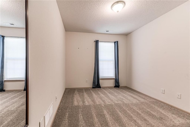 carpeted spare room with a textured ceiling