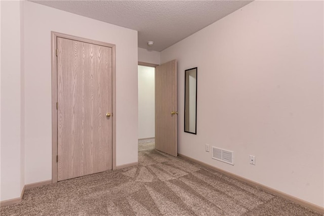 unfurnished bedroom with light colored carpet, a closet, and a textured ceiling