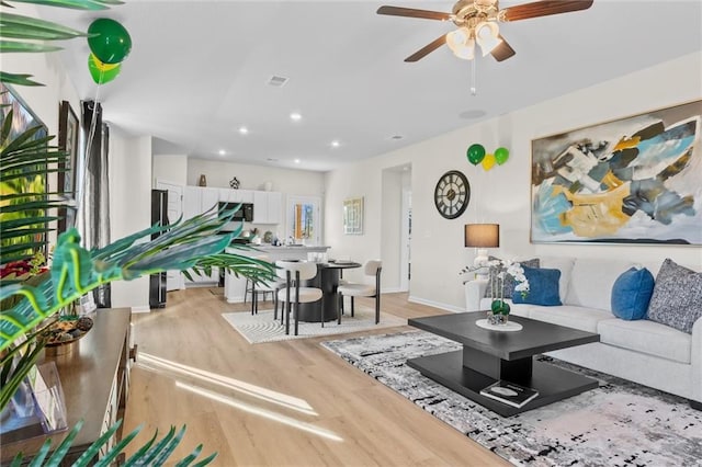 living room with ceiling fan and light hardwood / wood-style flooring