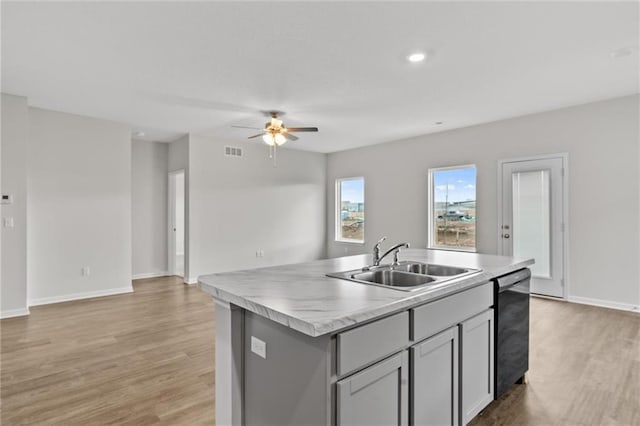 kitchen with an island with sink, ceiling fan, black dishwasher, gray cabinetry, and sink