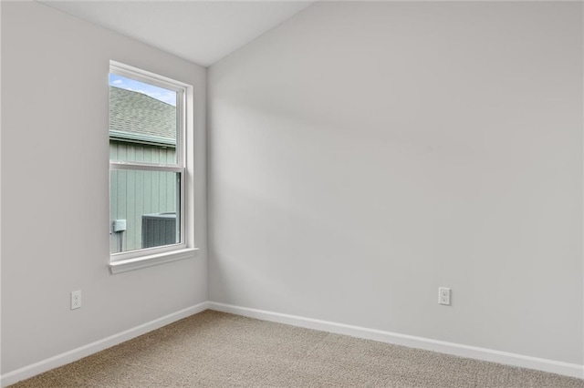 carpeted empty room with baseboards and lofted ceiling