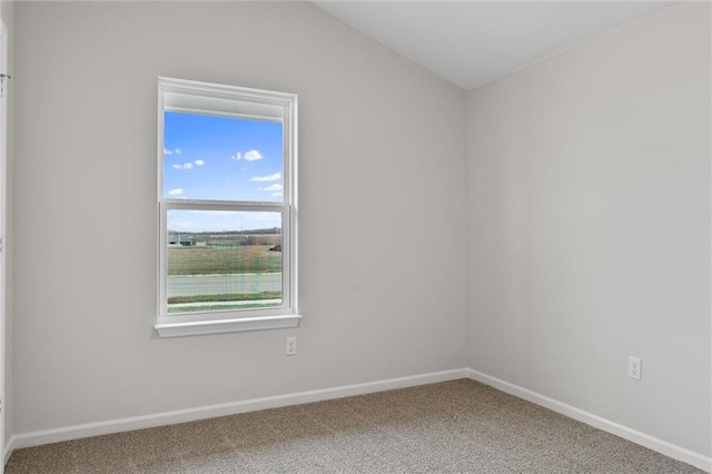 unfurnished room featuring carpet, baseboards, and vaulted ceiling