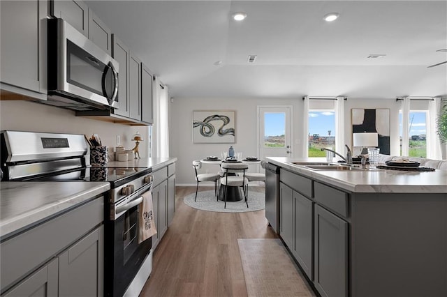 37767 W 207th Ter, Edgerton, KS 66021 - kitchen with appliances with stainless steel finishes, gray cabinets, light wood finished floors, light countertops, and a center island with sink