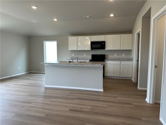 37767 W 207th Ter, Edgerton, KS 66021 - kitchen with black microwave, white cabinets, stove, wood finished floors, and an island with sink