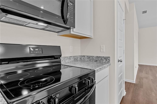 kitchen featuring black appliances, white cabinets, light stone counters, and light hardwood / wood-style floors