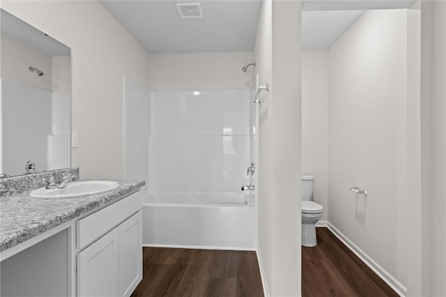 full bathroom featuring toilet, wood-type flooring, vanity, and bathtub / shower combination