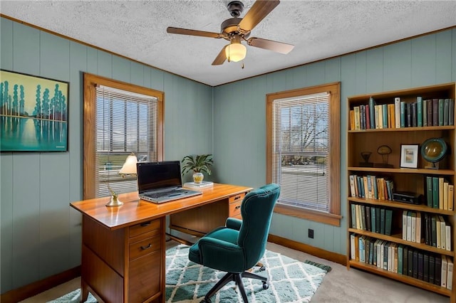 office area featuring ceiling fan, light colored carpet, wooden walls, and a textured ceiling