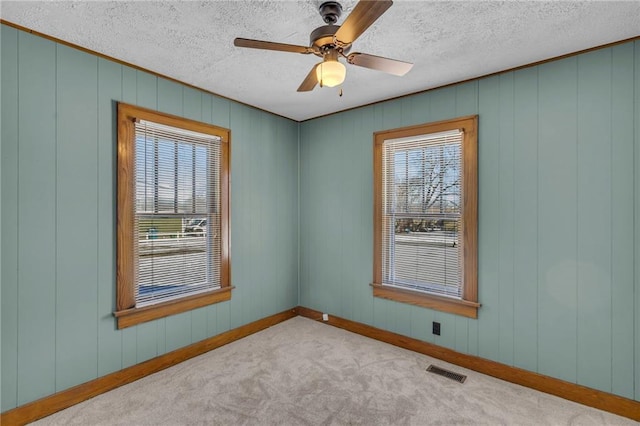 carpeted spare room featuring a textured ceiling and ceiling fan