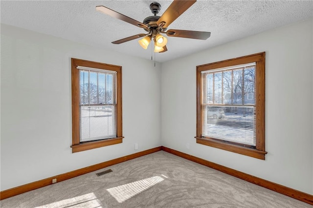 unfurnished room featuring a textured ceiling, ceiling fan, and light colored carpet