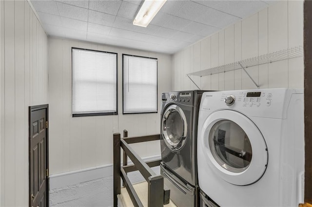 laundry area with wood walls and washing machine and clothes dryer