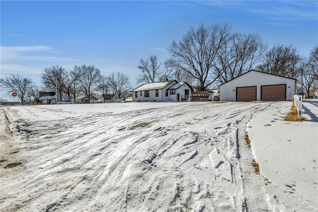 snowy yard with a garage and an outdoor structure