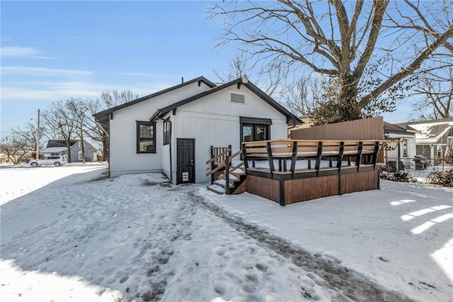 snow covered rear of property with a wooden deck