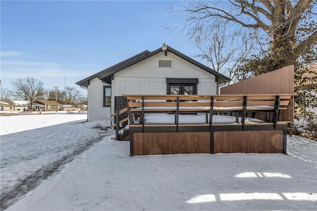 snow covered rear of property with a deck