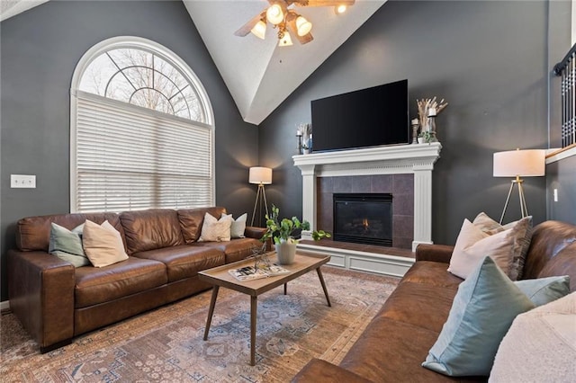 living room featuring ceiling fan, lofted ceiling, and a tile fireplace