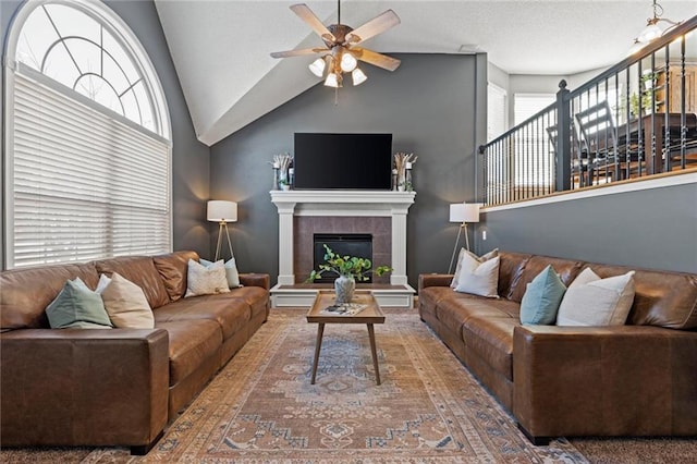 living room featuring ceiling fan, plenty of natural light, a tile fireplace, and lofted ceiling