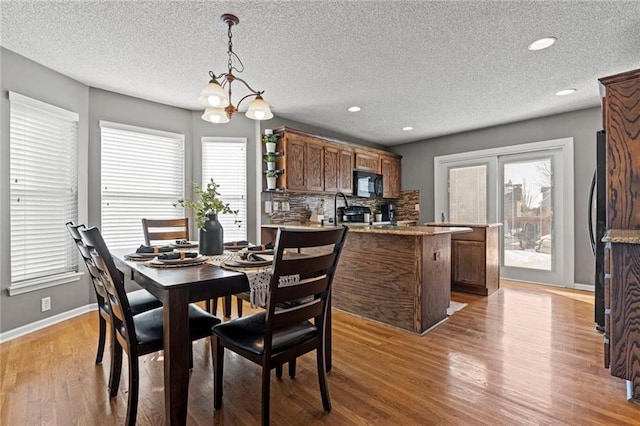 dining space with a notable chandelier, a textured ceiling, and light hardwood / wood-style floors