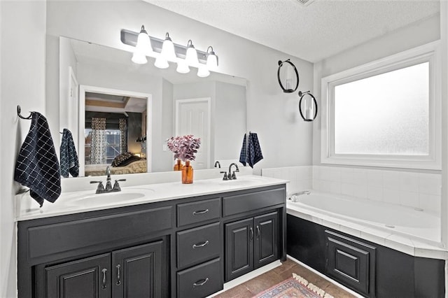 bathroom with a tub, a textured ceiling, and vanity