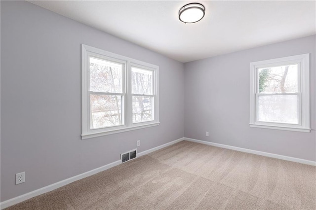 empty room featuring light colored carpet and a healthy amount of sunlight