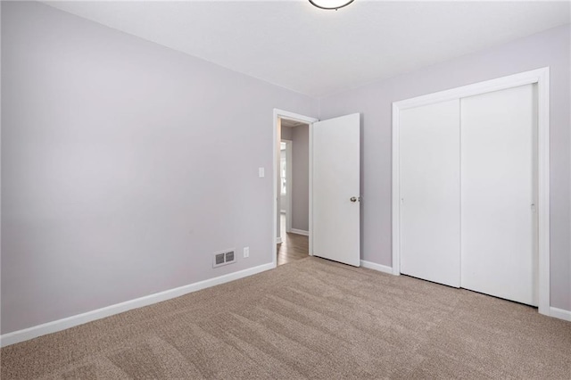 unfurnished bedroom with light carpet and a closet