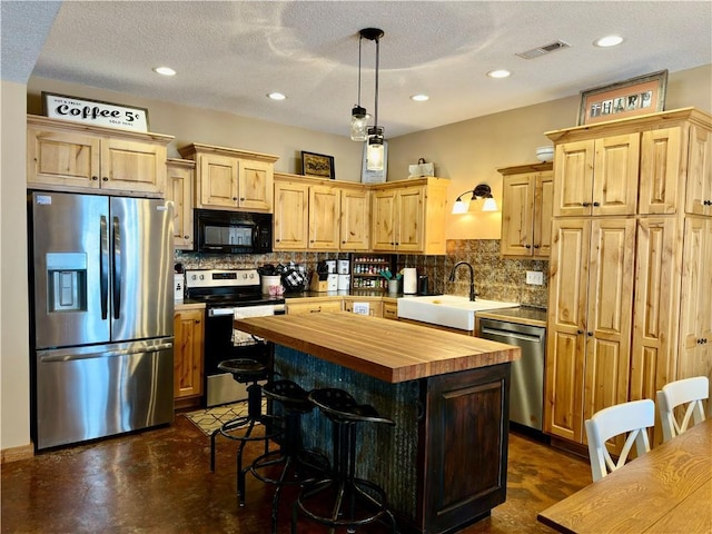 kitchen with wooden counters, stainless steel appliances, hanging light fixtures, a kitchen island, and sink