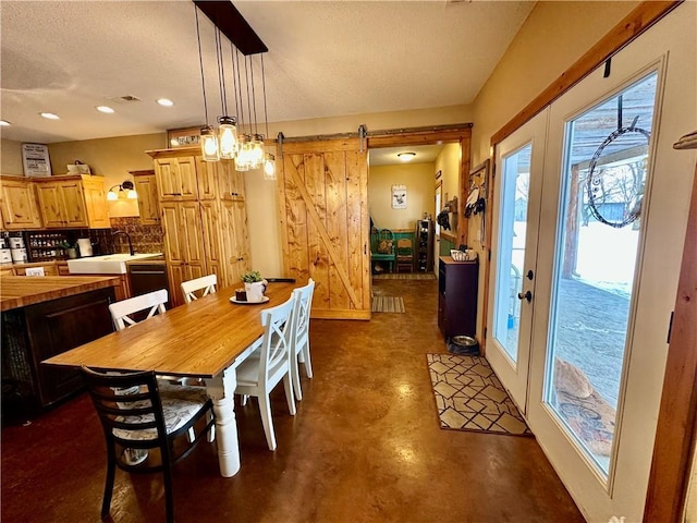 dining room with a barn door and a textured ceiling