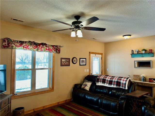 living room featuring ceiling fan and a textured ceiling