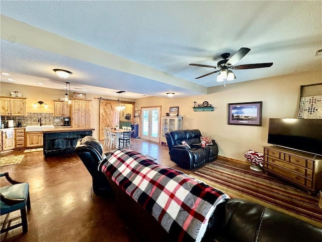 living room featuring ceiling fan, sink, and a textured ceiling