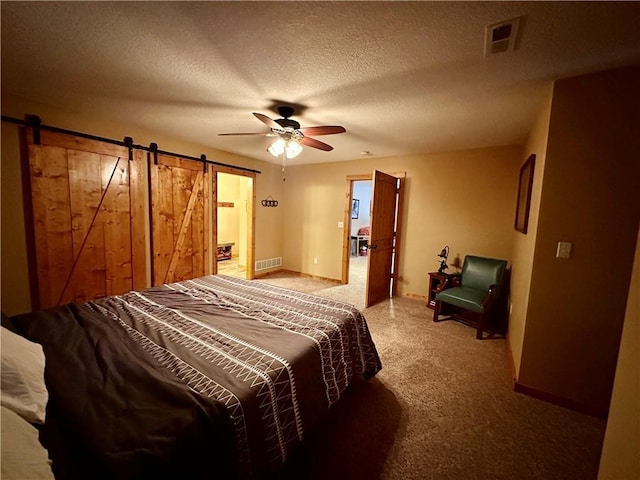 bedroom featuring ceiling fan, a textured ceiling, and a barn door