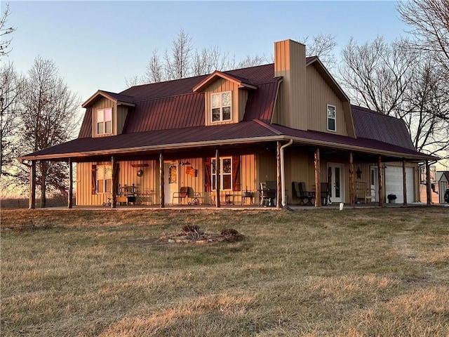 back house at dusk featuring a porch, a garage, and a yard