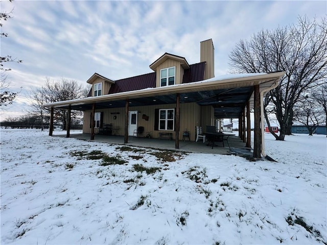 snow covered back of property with a porch