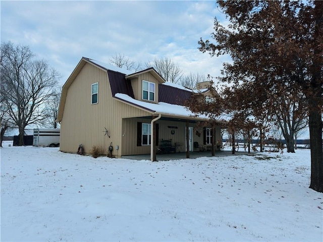 snow covered house featuring covered porch