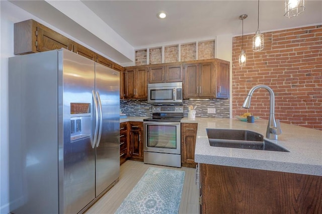 kitchen featuring appliances with stainless steel finishes, pendant lighting, sink, backsplash, and kitchen peninsula