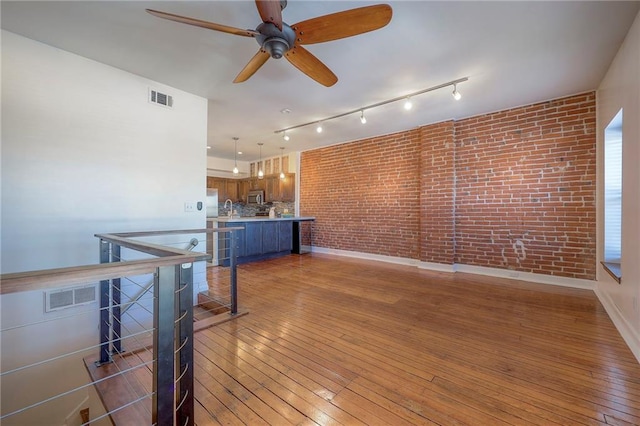 living room with brick wall, sink, and light hardwood / wood-style flooring