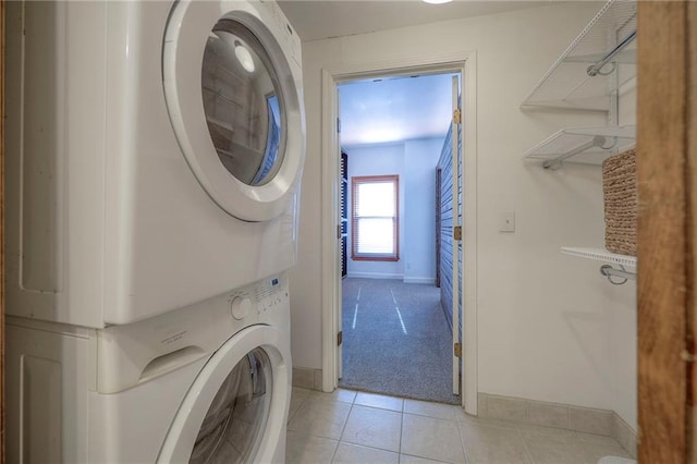 laundry area featuring light tile patterned floors and stacked washing maching and dryer