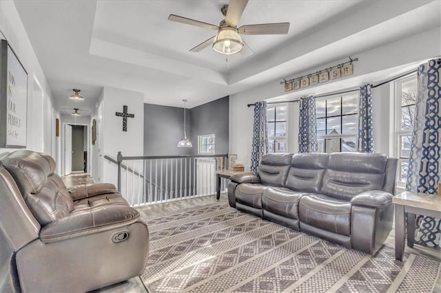 living room with ceiling fan and a raised ceiling