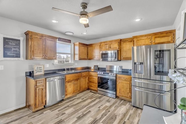 kitchen with light wood-type flooring, ceiling fan, stainless steel appliances, and sink