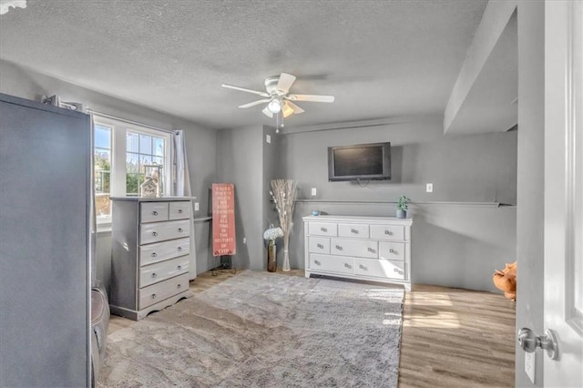 bedroom featuring ceiling fan, a textured ceiling, and light hardwood / wood-style flooring